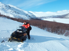 St&aring;lis frees his snowmobile from deep snow on Varregaska, head of the lake behind